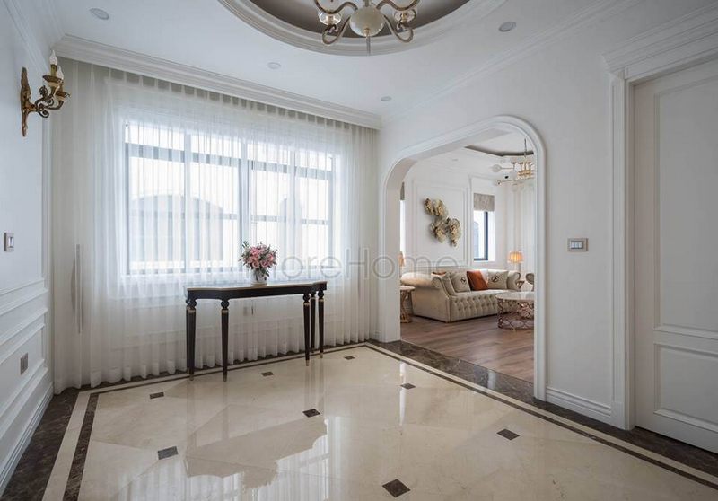 Tất cả những ánh nhìn được tập trung vào kệ trang trí đặt trước cửa lớn tinh tế được bao quanh bởi rèm trắng nhẹ mỏng.